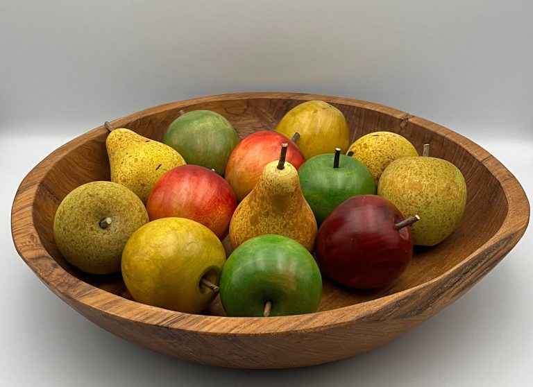 A wooden bowl filled with various hand crafted apples and pears in different colours.